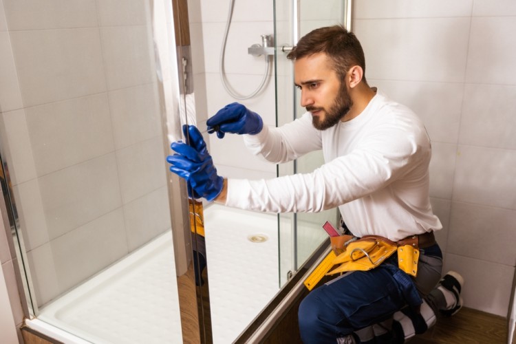 Plumber installing shower cabin in bathroom